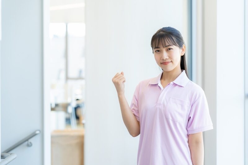 明るい廊下でガッツポーズをする女性介護スタッフ