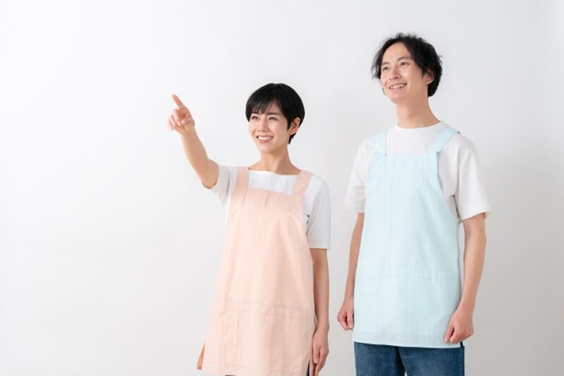 エプロン姿で指差しをする男女介護スタッフ